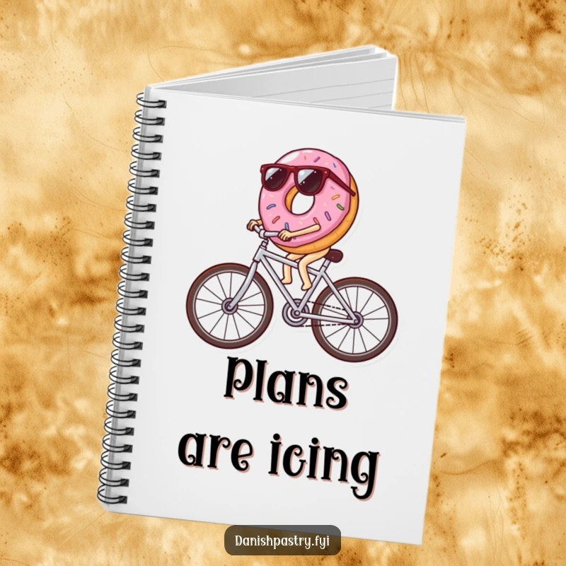 Funny donut wearing sunglasses riding a bicycle made of icing streaks, a cool and humorous notebook for capturing creative thoughts.