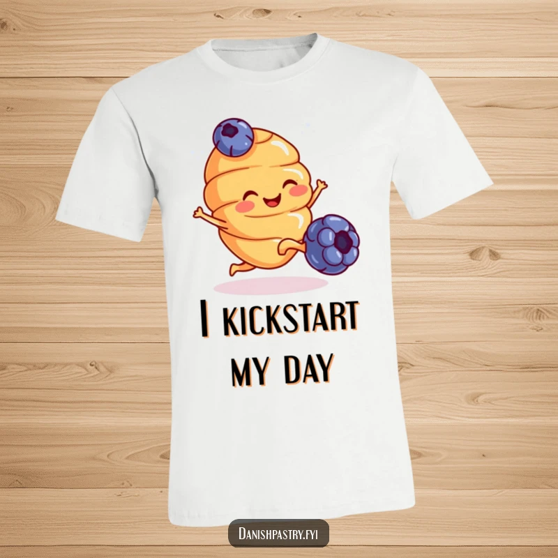 Funny T-Shirt: A smiling croissant with tiny legs excitedly kicks a blueberry, celebrating breakfast with energetic silliness.